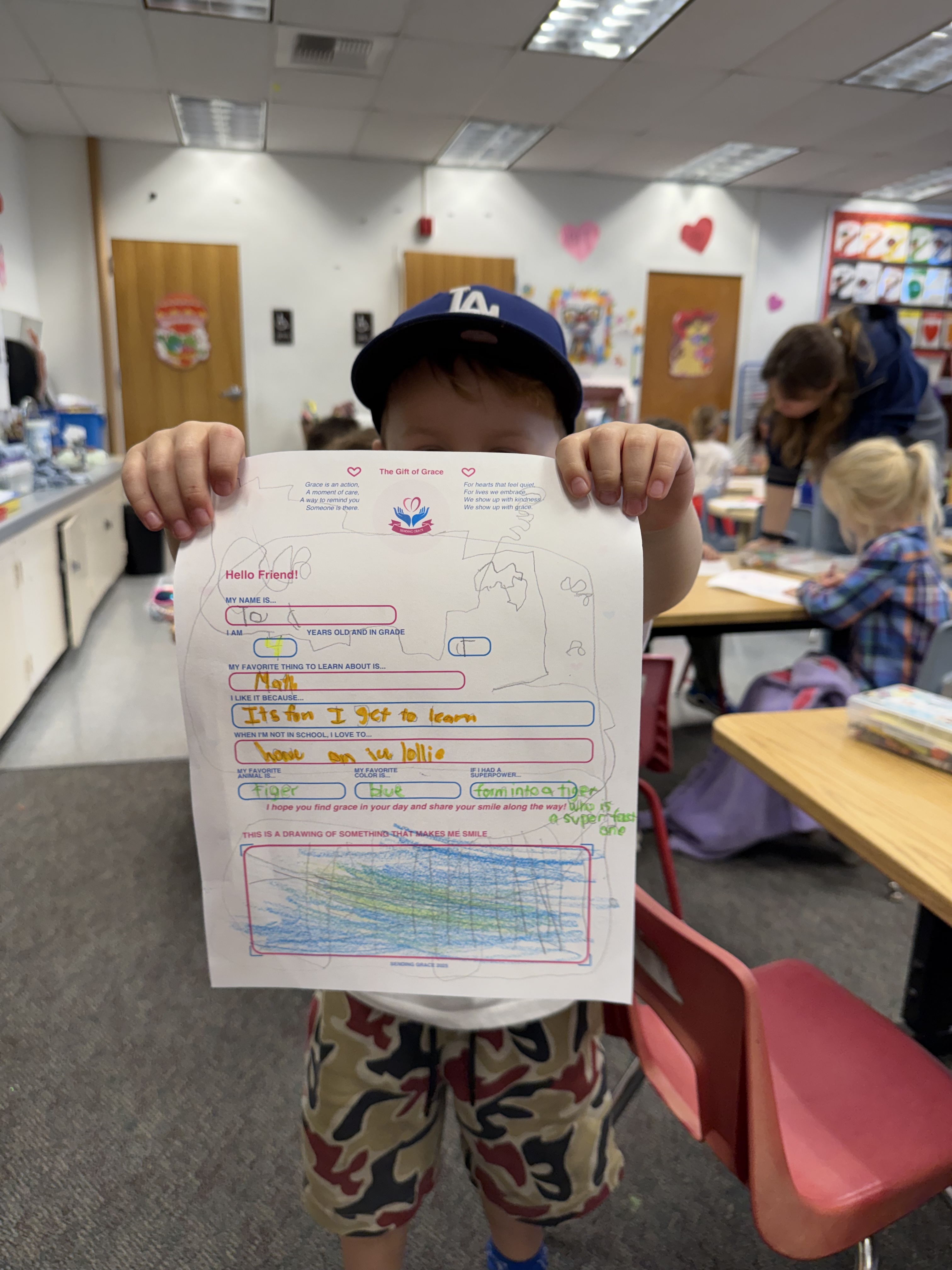 A child in a Dodgers hat holding up his completed Sending Grace letter
