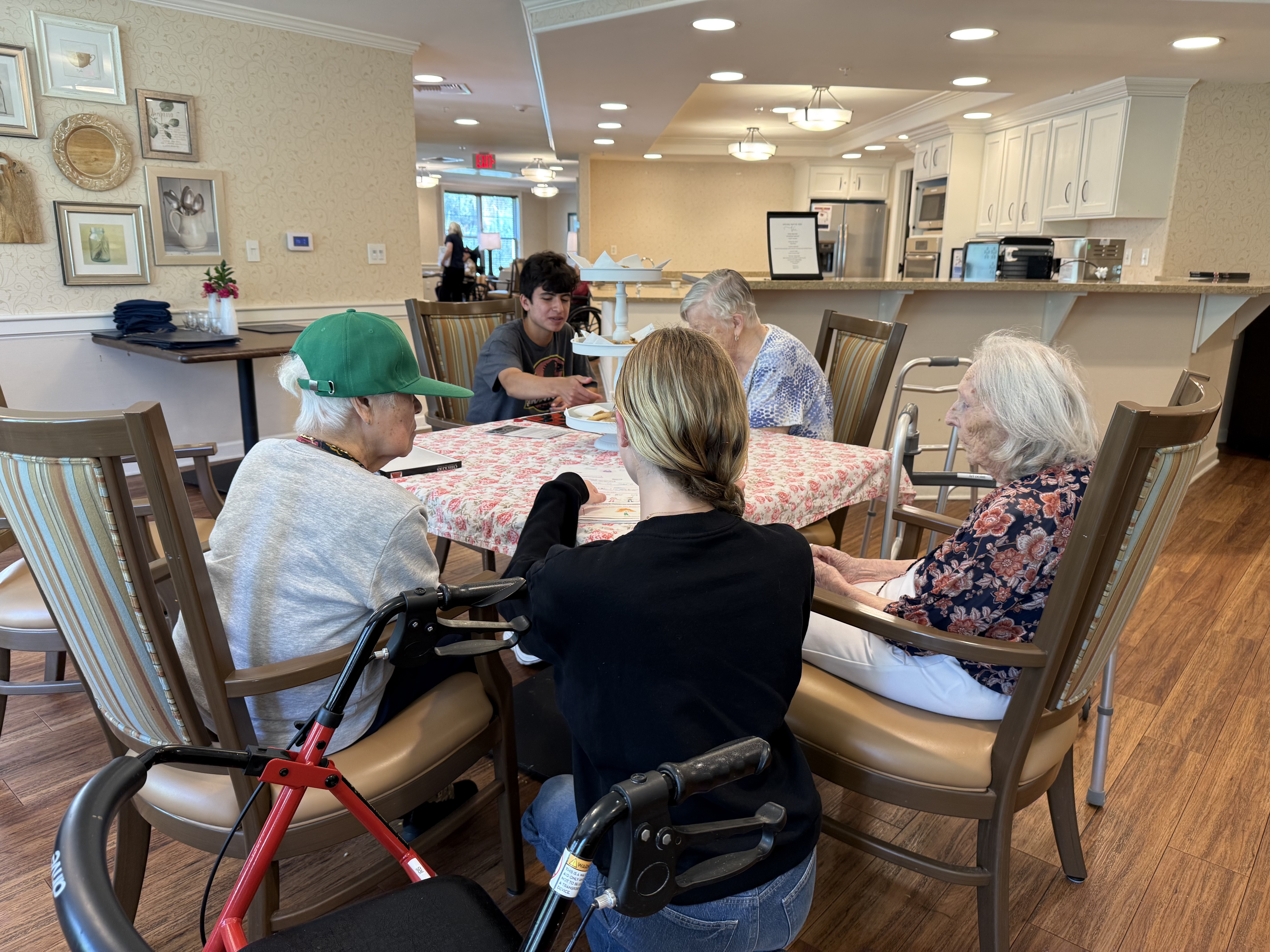 Grace reading a letter with a resident at a table