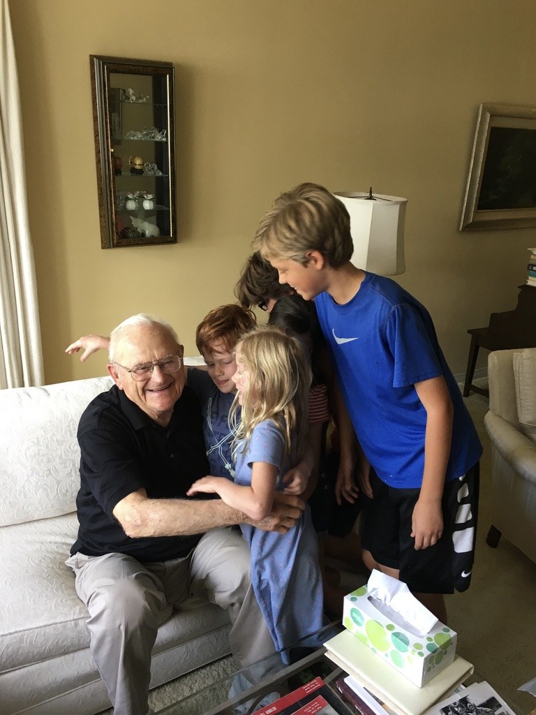 Mr. Peck laughing as Grace and her cousins hug him on his couch